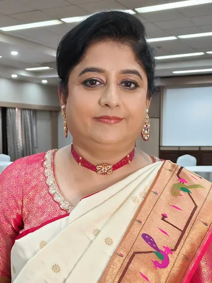 A close-up of the mother of the bride, ready for the Haldi ceremony. Her makeup is fresh and natural, with a soft lip color that complements her beautiful Paithani saree. Her hair is styled in a classic, neat updo.