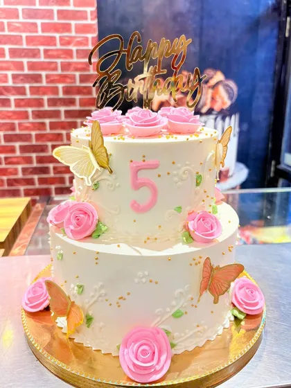 A lovely two-tier cake for a 5th birthday, decorated with pink sugar roses and delicate edible butterflies.