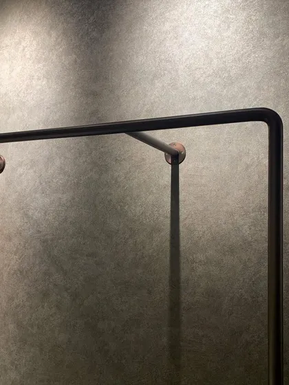 A detail of a custom metal railing. The clean lines, the subtle curve, and the contrast between the dark metal and the textured wall behind it showcase a distilled beauty that energizes the space.