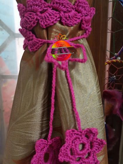 This curtain tie-back is made with a band of beautiful magenta flowers. The matching ties end in smaller flowers, creating a lush, floral look for your curtains.