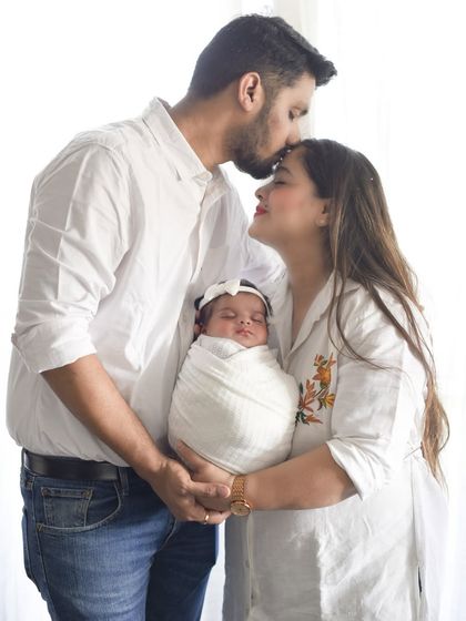 A beautiful family portrait with a newborn. The coordinated white outfits create a bright, airy, and pure look, while the loving poses show the deep connection of the new family.