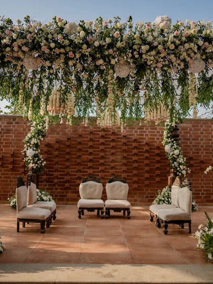 I believe in versatility, creating designs that reflect each couple's unique style. This modern mandap, with its elegant white and green floral design against a rustic brick wall, showcases a contemporary aesthetic that is both romantic and sophisticated.