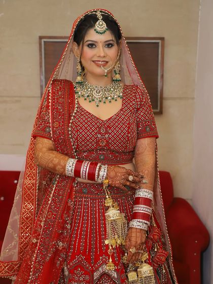 A full-length shot showcasing how the makeup, hair, and stunning red lehenga come together for a complete, breathtaking bridal look.