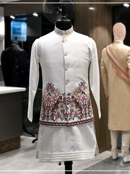 A full view of the white Nehru jacket with the tiger and floral print, paired with a simple white kurta.