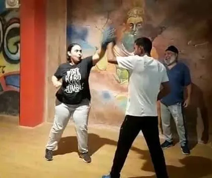 A female participant at our fitness camp learns basic boxing techniques, proving that anyone can start their journey to becoming stronger and safer.