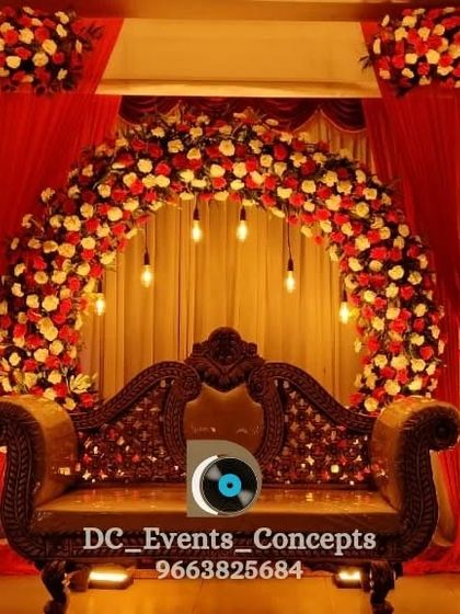 A classic engagement stage with a beautiful arch of red and white roses. The traditional carved sofa and warm lighting create a timeless and romantic backdrop for the couple.