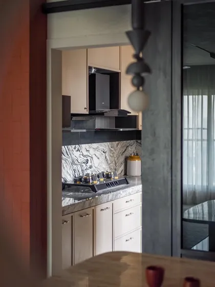 A peek into the kitchen from the dining area. The design is clean and modern, with a beautiful marble backsplash and sleek cabinets.
