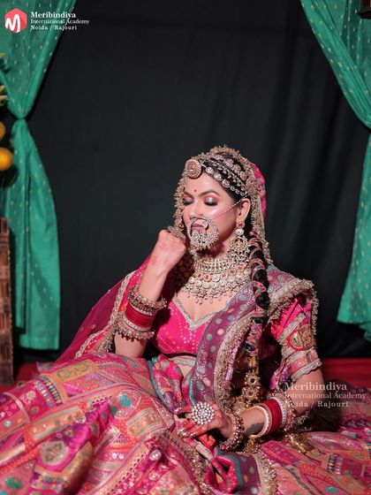 A full view of the bride seated, displaying the rich fabric of her lehenga and the complete, regal look created by our students.