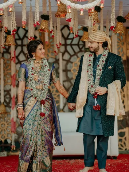 A beautiful couple portrait after their grand Muhurtham. The intricate details of their attire and the traditional temple mandap in the background create a stunning composition.