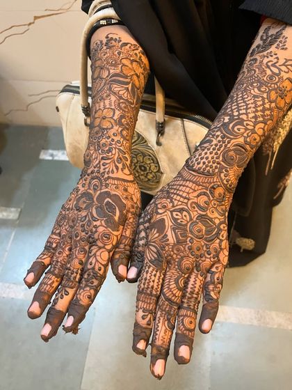 The full view of a semi bridal mehndi, with both hands adorned in rich, dense patterns.