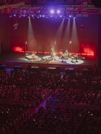 A wide shot of the Anoushka Shankar concert, showing the full band on a beautifully lit stage in a large auditorium.