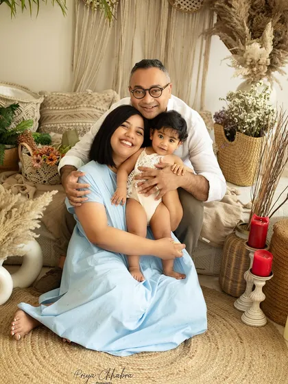 A happy family portrait during a milestone session. The natural tones and textures of the studio create a warm and inviting atmosphere for everyone to relax.