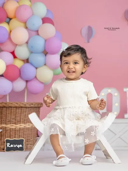 A full view of our hot air balloon setup, complete with pastel balloons, light-up signs, and a very happy one-year-old ready to celebrate.