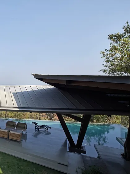 The angled roof of the Lateral Verandah House extends over the infinity pool, providing shade and framing the horizon. This design choice is both functional and poetic, enhancing the experience of being suspended between the earth and the sky.