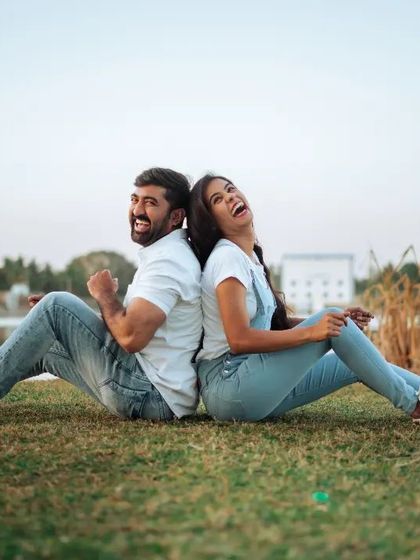 A fun and playful moment from a casual couple's shoot by a lake. The back-to-back pose and genuine laughter show a different, more lighthearted side of relationship photography.