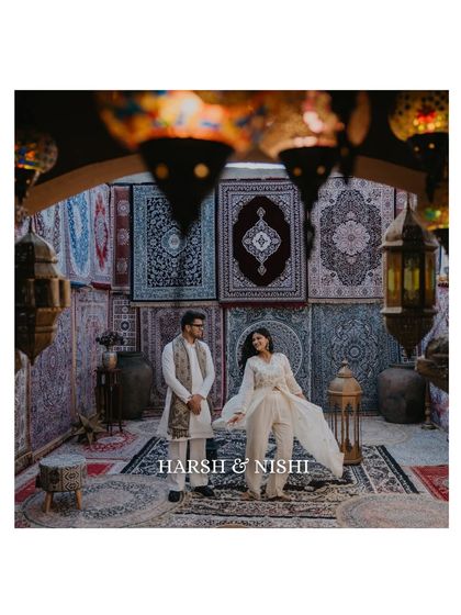 A beautifully composed shot of a couple in an ethnic-themed setting, surrounded by intricate carpets and lanterns. This image has a rich, cultural, and almost regal feel.