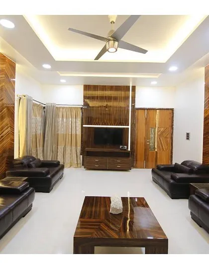This living room is defined by its warmth and elegance. We used extensive, high-gloss wood paneling with a striking grain to create a sense of grandeur and cohesion. The layout is designed for conversation and comfort, featuring plush leather sofas and carefully planned ambient and recessed lighting.