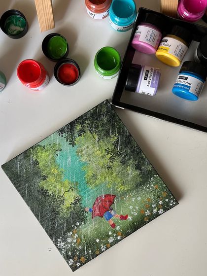 An overhead shot of the rainy day painting next to the open set of acrylic paints.