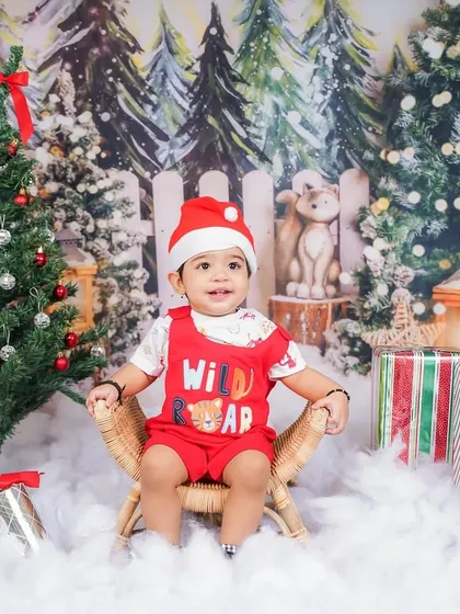 This little one is ready for Christmas, sitting by the tree in a festive outfit. My studio is equipped with various holiday-themed backdrops and props.