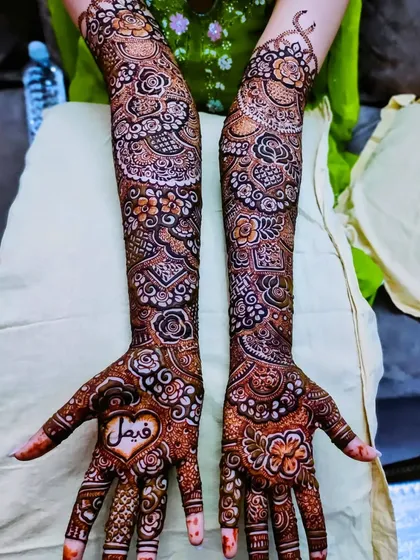 A lovely bridal design with the groom's name, 'Faisal', written inside a heart on the palm.