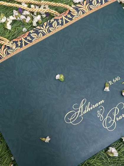 A carry-bag for a deep blue and gold invitation suite, featuring a traditional floral border and sturdy rope handle.