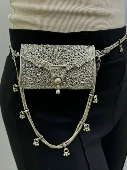 An exclusive silver purse that can also be worn as a belt bag. This versatile piece features intricate carving and dangling silver bells, making your outfit shine from every angle.