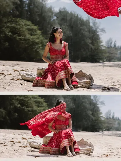 The bride's vibrant red dupatta flies in the ocean breeze, creating a stunning visual against the beach backdrop. This shot is a perfect blend of traditional elegance and the carefree spirit of a destination wedding.