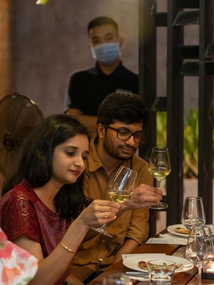 A couple inspects their glasses of white wine, fully immersed in the tasting experience.