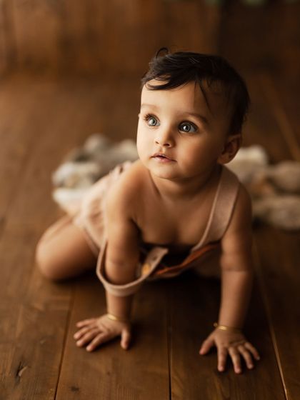 Those beautiful eyes. This little one is captured in a moment of quiet curiosity while crawling on the wooden floor.
