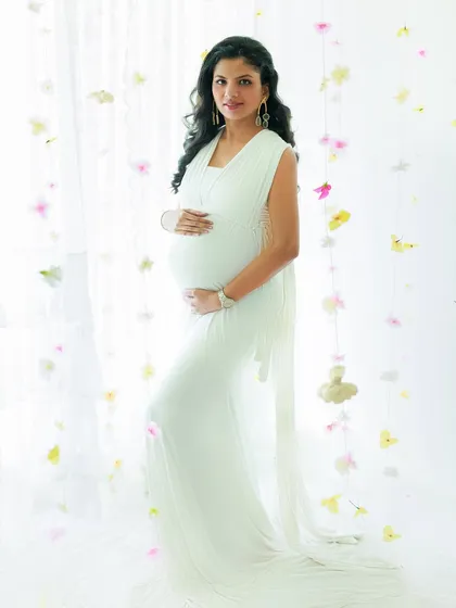 Cradling the miracle within. This mother-to-be looks like a goddess in a classic white gown, surrounded by a delicate curtain of flowers for an ethereal touch.
