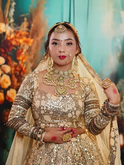 A frontal view of the golden bridal look, highlighting the intricate necklace and the clean, precise makeup application by our student.