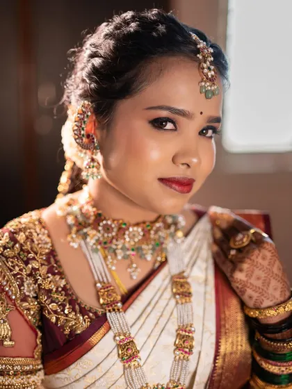 A close-up of a classic South Indian muhurtham look for Lavanya. The focus is on traditional details, with bold kohl-rimmed eyes, a classic red lip, and skin that looks luminous and real, even under the bright ceremony lights.