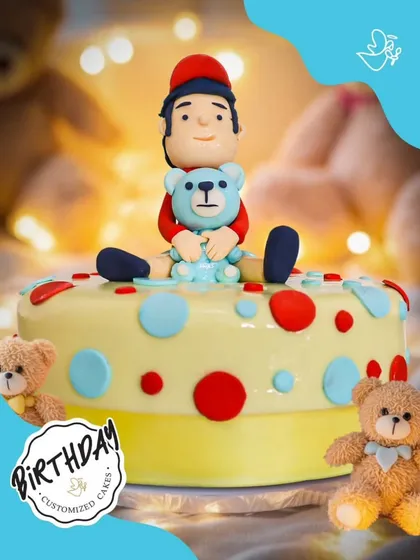 An adorable cake featuring a little boy and his teddy bear. The colorful polka dots and sweet fondant figures make this a heartwarming choice for a young child's birthday.