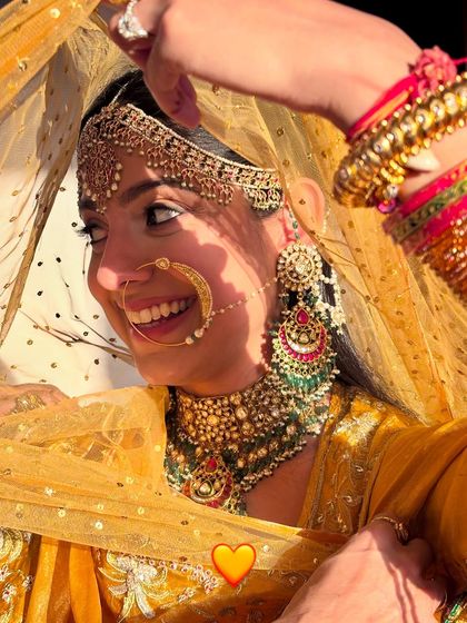A close-up of this bride's happy smile. Her heirloom yellow poshak and traditional jewelry are paired with simple, timeless makeup.