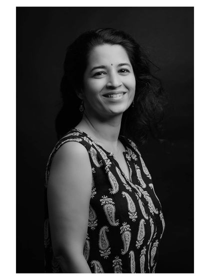 A classic studio portrait of a woman, where the black and white treatment highlights her natural smile and the movement in her hair.