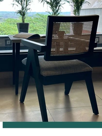 An overhead view of our Chandigarh Chair, highlighting the beautiful contrast between the woven cane back, the textured seat cushion, and the clean lines of the black oak frame. This piece is a study in classic form and modern comfort.