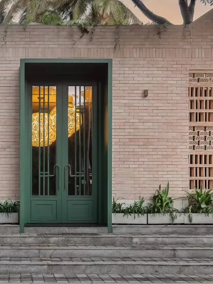 The entrance to Ishtaa restaurant sets a modern yet earthy tone with its clean brick facade and a bold green statement door. This exterior design hints at the warm, nature-inspired hospitality interior that awaits guests inside, creating a memorable first impression.