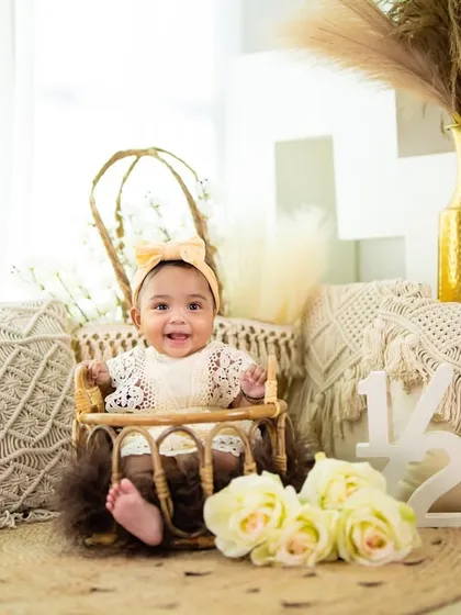 A bright and happy half-birthday girl in a bohemian-themed setup. The natural textures and soft light create a beautiful, airy portrait.