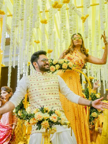 A close-up of the couple enjoying their unique Haldi entry, surrounded by floral decorations on the rickshaw.