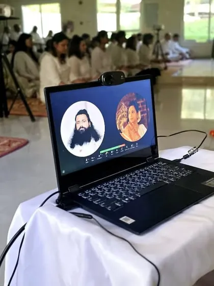This unique photo shows a hybrid setup where an in-person gathering is connected to our virtual session on a laptop. We bridge the physical and digital to unite as many seekers as possible.
