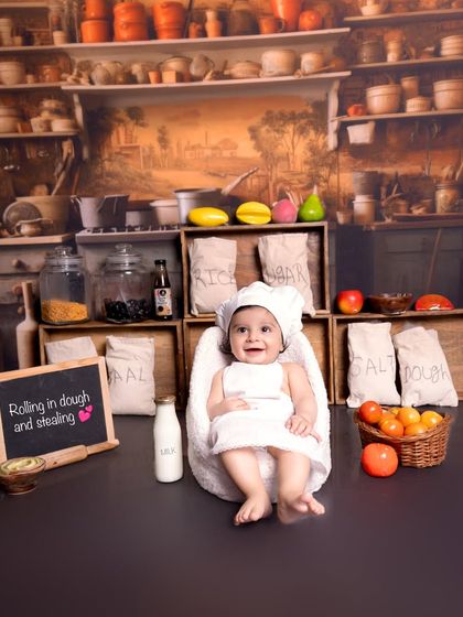 A happy smile from the star of our kitchen-themed session. I ensure the environment is fun and engaging for the baby, which helps in capturing these genuinely happy moments.
