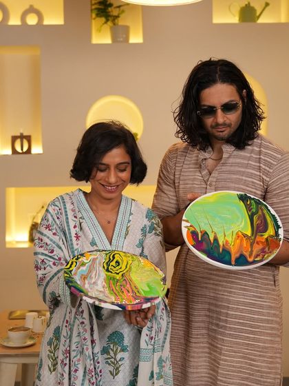 Sucharita and Ali showing off their finished fluid art pieces. Each one is a unique swirl of colors, reflecting their creative expression during the session.