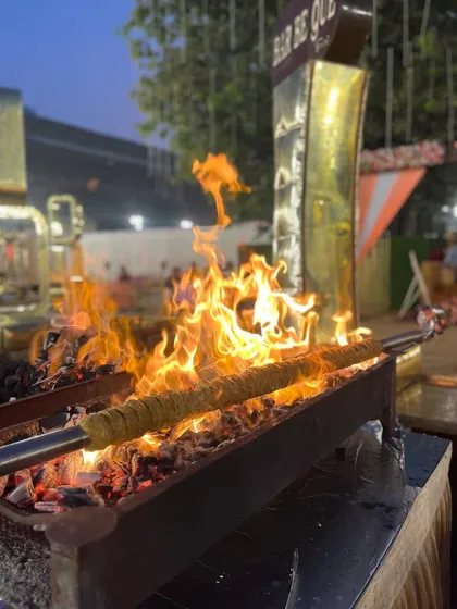 The flames leap up to kiss the Irani Seekh Kebabs, infusing them with a unique, smoky flavor that can only be achieved with live-fire cooking.