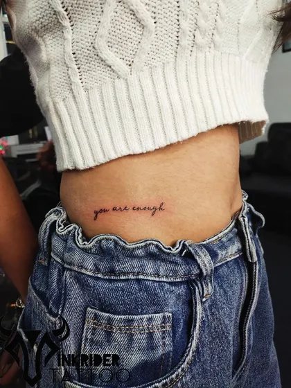A self-love reminder with the phrase "you are enough" tattooed on the hip. A simple, powerful affirmation in a delicate script.