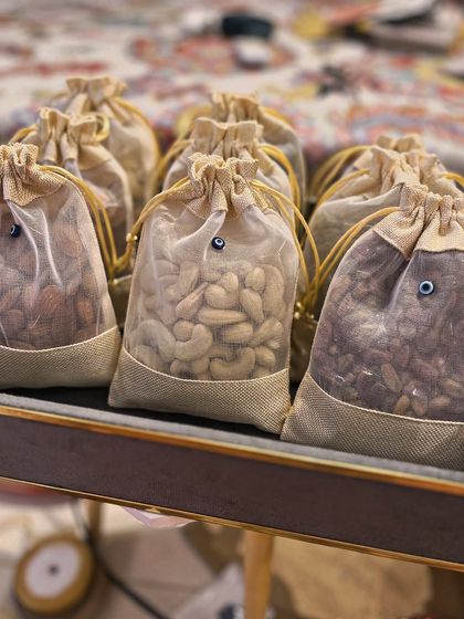 Dry fruits are packaged in simple yet elegant jute potlis, each adorned with a tiny evil eye bead. This detail ensures that every single element of the trousseau aligns with the protective and beautiful theme.