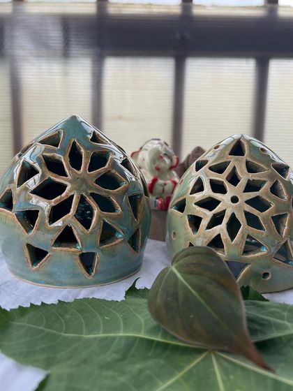 These teal-colored tea light holders have a beautiful star-like pattern carved into them. They look so serene resting on a green leaf.