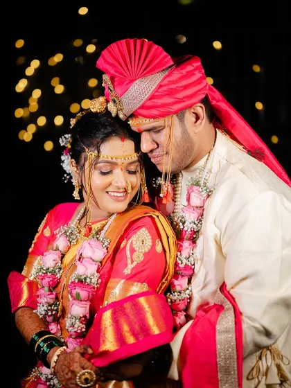 An intimate couple portrait against a backdrop of bokeh lights. The bride's Nauvari saree and the groom's matching turban create a perfect picture.