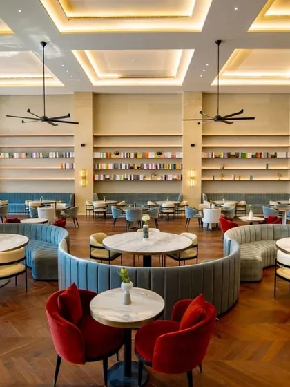 The main hall of the Elevate Clubhouse is designed for both grandeur and comfort. The arrangement of circular and curved seating breaks up the large space into more intimate zones, while pops of red add energy and visual interest.