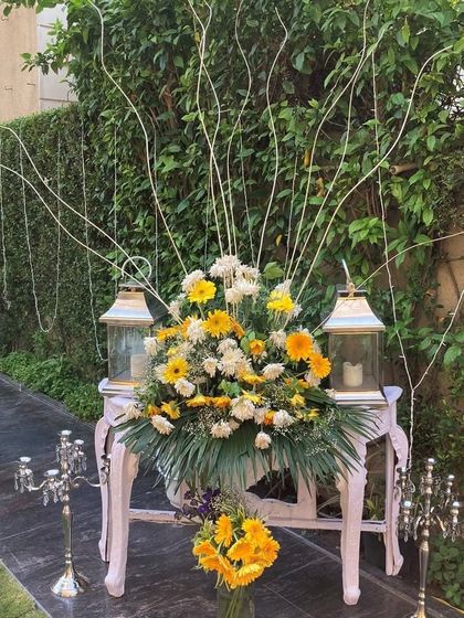 A beautiful floral arrangement for an outdoor event. We used a mix of yellow and white flowers with elegant lanterns to create a welcoming and picturesque corner.