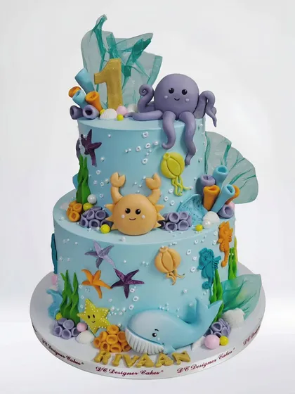 A beautiful two-tier underwater theme cake for a first birthday. This whipped cream cake is decorated with a friendly octopus, crab, whale, and other sea creatures.